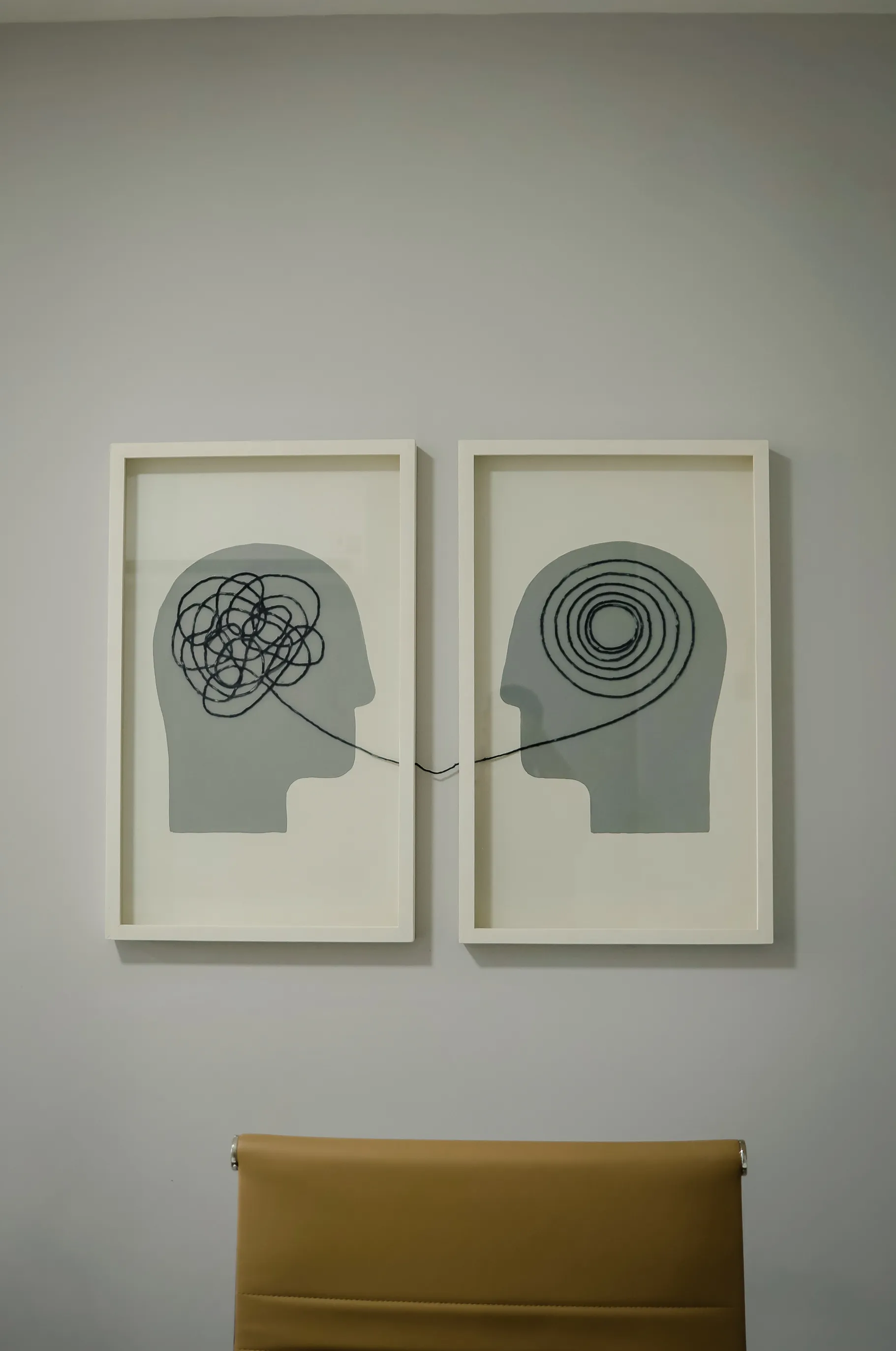 Quadros do consultório: uma cabeça com linha emaranhada e outra com a linha organizada em espiral, ligadas por um mesmo fio